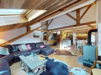 Experience rustic charm in this spacious living area, featuring exposed wooden beams and a vaulted ceiling with skylights for abundant natural light.