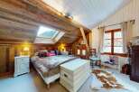 Experience rustic charm in this cozy attic bedroom, featuring exposed wooden beams and a skylight offering mountain views.