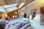 Experience rustic charm in this cozy attic bedroom, featuring a sloped wooden ceiling and a large skylight that floods the space with natural light.