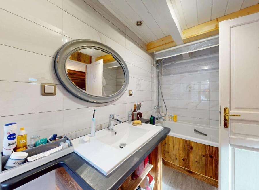 This charming bathroom features a sleek white vanity with a modern sink and faucet, complemented by a large, ornate mirror.