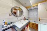This charming bathroom features a sleek white vanity with a modern sink and faucet, complemented by a large, ornate mirror.