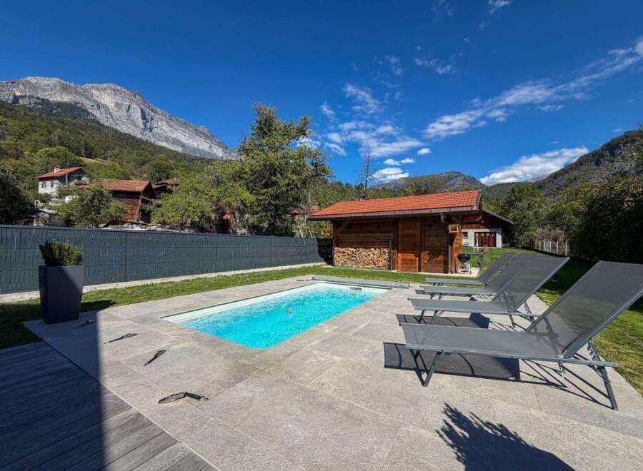 Experience ultimate relaxation in this stunning property featuring a pristine swimming pool and comfortable lounge chairs, perfect for soaking up the sun.