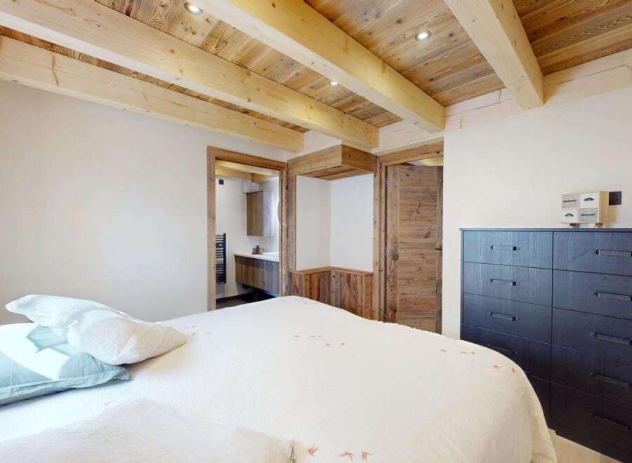 Experience rustic charm in this bedroom, featuring exposed wooden beams and natural wood paneling for a cozy alpine feel.