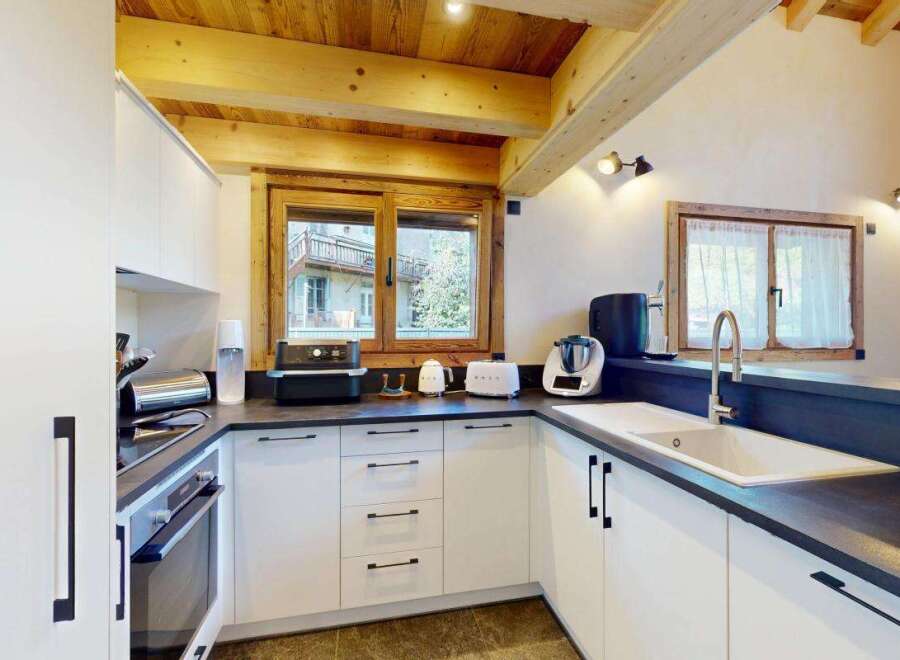 Experience modern comfort in this beautifully appointed kitchen, featuring sleek white cabinetry and a dark countertop.