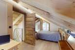 Experience rustic charm in this attic bedroom, featuring exposed wooden beams and a cozy, sloped ceiling.