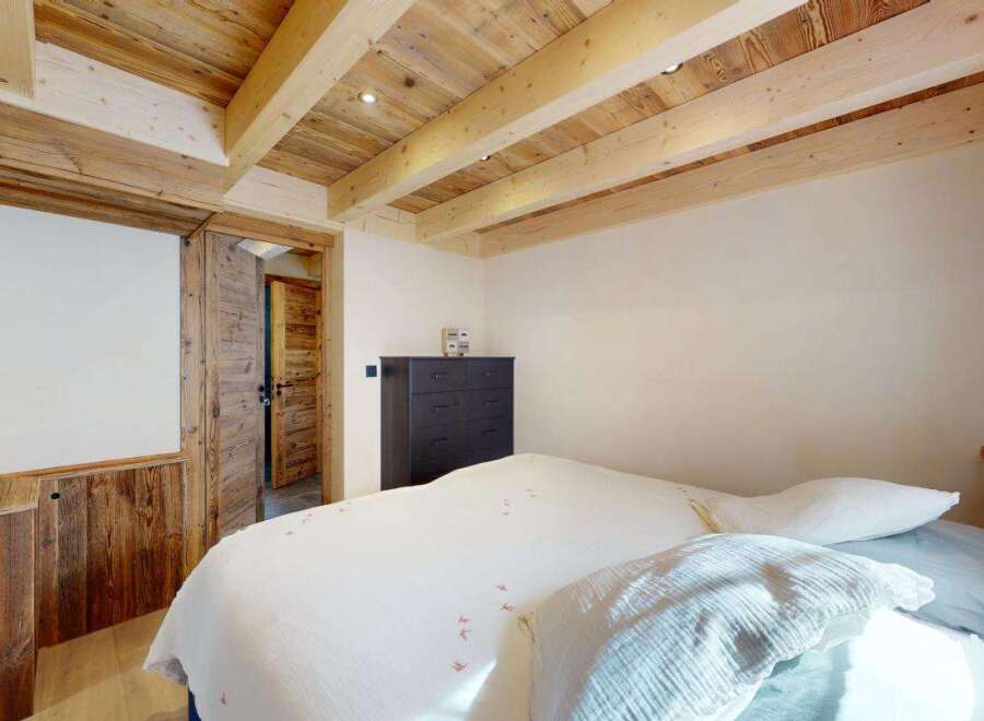 Experience rustic charm in this cozy bedroom, featuring a beautifully paneled wooden ceiling with exposed beams and recessed lighting.