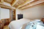 Experience rustic charm in this cozy bedroom, featuring a beautifully paneled wooden ceiling with exposed beams and recessed lighting.