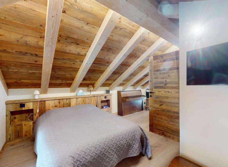 Experience rustic charm in this cozy bedroom featuring a beautifully paneled wooden ceiling and walls, creating a warm and inviting atmosphere.