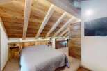 Experience rustic charm in this cozy bedroom featuring a beautifully paneled wooden ceiling and walls, creating a warm and inviting atmosphere.