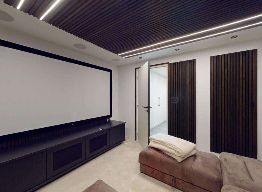 Experience cinematic bliss in this modern home theater, featuring a massive projection screen and plush seating for ultimate comfort.