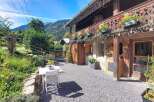 Experience the charm of this rustic mountain retreat, featuring a wooden balcony adorned with vibrant red flowers and intricate carvings.