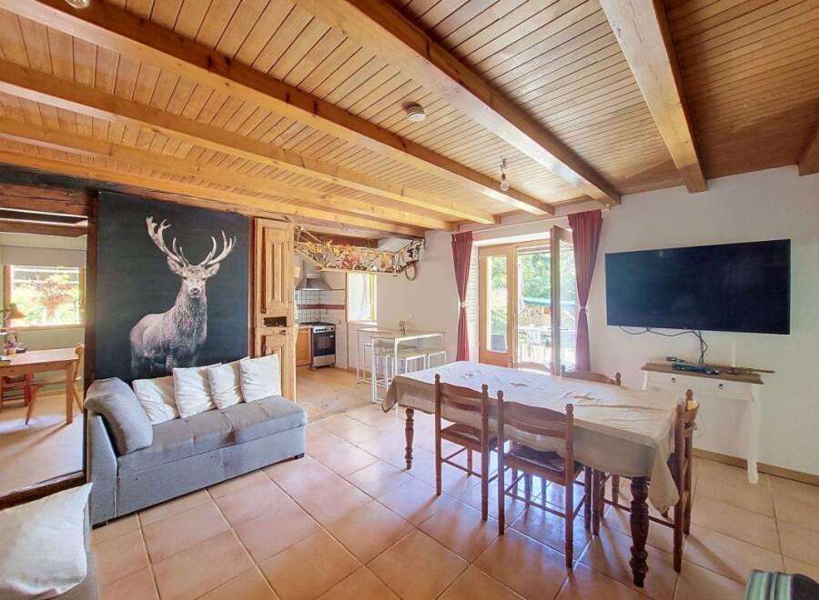 Experience rustic charm in this open-plan living and dining area, featuring a striking stag mural and exposed wooden beams.