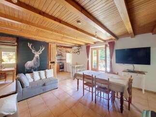 Experience rustic charm in this open-plan living and dining area, featuring a striking stag mural and exposed wooden beams.