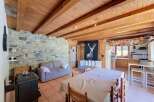 Experience rustic charm in this cozy living space featuring a stone accent wall and exposed wooden beams.