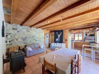 Experience rustic charm in this cozy living space featuring a stone accent wall and exposed wooden beams.