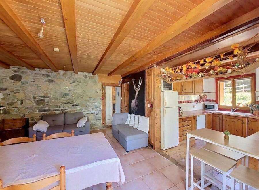 Experience rustic charm in this cozy living space featuring exposed wooden beams and a stone accent wall.
