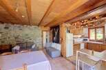 Experience rustic charm in this cozy living space featuring exposed wooden beams and a stone accent wall.