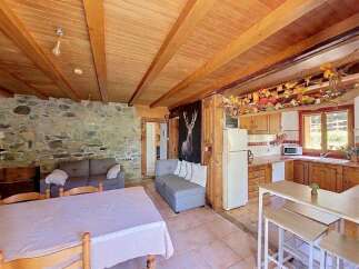 Experience rustic charm in this cozy living space featuring exposed wooden beams and a stone accent wall.