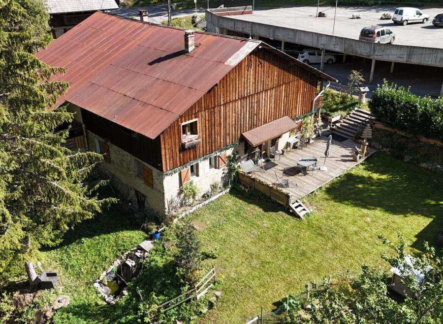 Discover this charming property featuring a rustic wooden house with a weathered red metal roof, complemented by a spacious wooden deck perfect for outdoor entertaining.