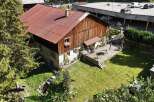 Discover this charming property featuring a rustic wooden house with a weathered red metal roof, complemented by a spacious wooden deck perfect for outdoor entertaining.