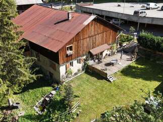 Discover this charming property featuring a rustic wooden house with a weathered red metal roof, complemented by a spacious wooden deck perfect for outdoor entertaining.