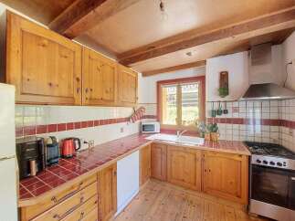 This charming kitchen features warm wooden cabinetry and a rustic tiled backsplash, creating a cozy and inviting atmosphere.