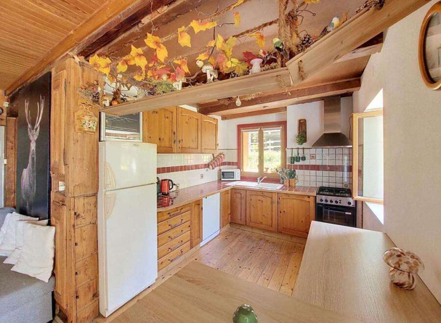This charming rustic kitchen features warm wooden cabinetry and countertops, complemented by a white refrigerator and a classic tiled backsplash.