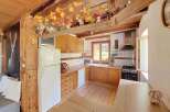 This charming rustic kitchen features warm wooden cabinetry and countertops, complemented by a white refrigerator and a classic tiled backsplash.
