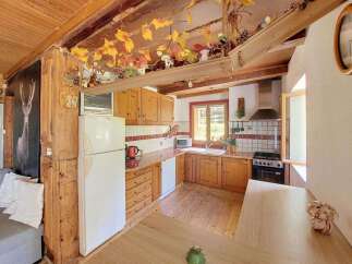 This charming rustic kitchen features warm wooden cabinetry and countertops, complemented by a white refrigerator and a classic tiled backsplash.