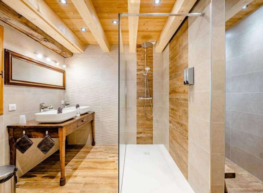 Experience rustic charm and modern luxury in this stunning bathroom featuring exposed wooden beams and a spacious walk-in shower with wood-look tile accents.