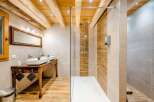 Experience rustic charm and modern luxury in this stunning bathroom featuring exposed wooden beams and a spacious walk-in shower with wood-look tile accents.