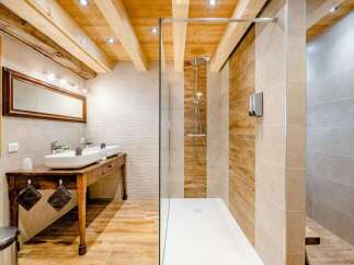 Experience rustic charm and modern luxury in this stunning bathroom featuring exposed wooden beams and a spacious walk-in shower with wood-look tile accents.