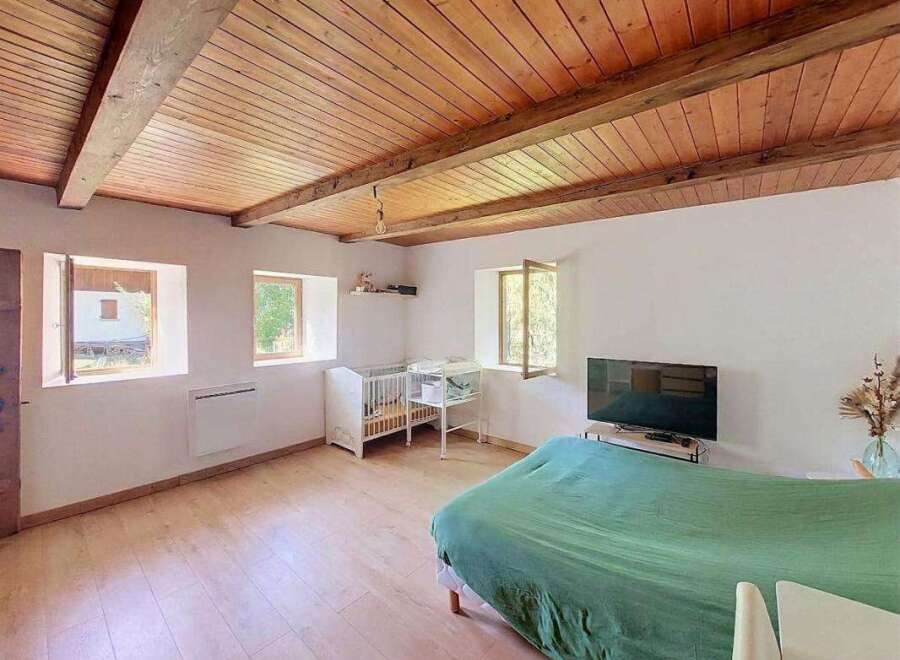 This charming room features a rustic wooden beamed ceiling and light wood floors, creating a warm and inviting atmosphere.