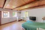 This charming room features a rustic wooden beamed ceiling and light wood floors, creating a warm and inviting atmosphere.