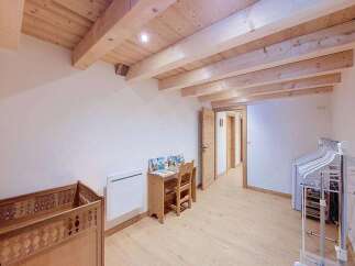 Discover this charming room featuring a rustic wooden crib and a quaint desk area, perfect for a child's space.