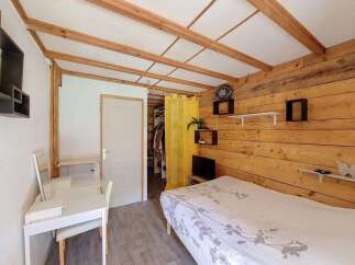 Discover this charming bedroom featuring a cozy bed with a nature-inspired duvet and a functional white desk area, perfect for work or study.