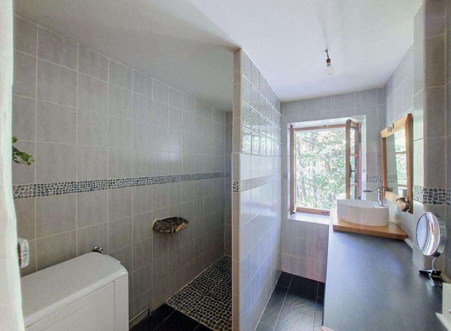 This modern bathroom features a spacious walk-in shower with elegant grey tiling and a unique stone shelf.