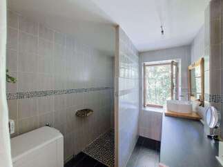 This modern bathroom features a spacious walk-in shower with elegant grey tiling and a unique stone shelf.