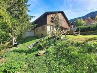 Nestled amidst lush greenery, this charming property offers a serene escape with its rustic wooden facade and stone accents.