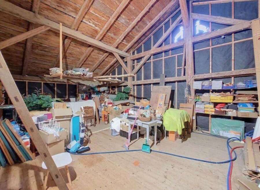Discover the potential of this spacious attic, featuring exposed wooden beams and ample storage solutions.