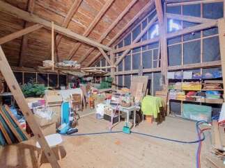 Discover the potential of this spacious attic, featuring exposed wooden beams and ample storage solutions.