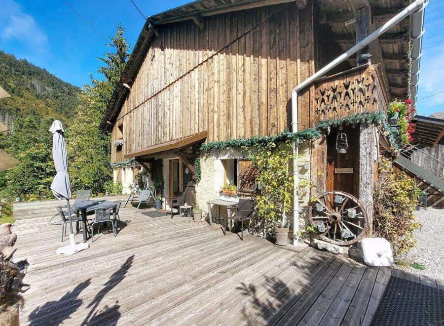 Enjoy the rustic charm of this wooden chalet, nestled against a backdrop of lush green mountains.