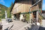 Enjoy the rustic charm of this wooden chalet, nestled against a backdrop of lush green mountains.