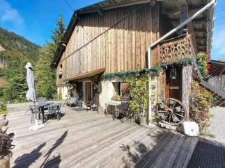 Enjoy the rustic charm of this wooden chalet, nestled against a backdrop of lush green mountains.