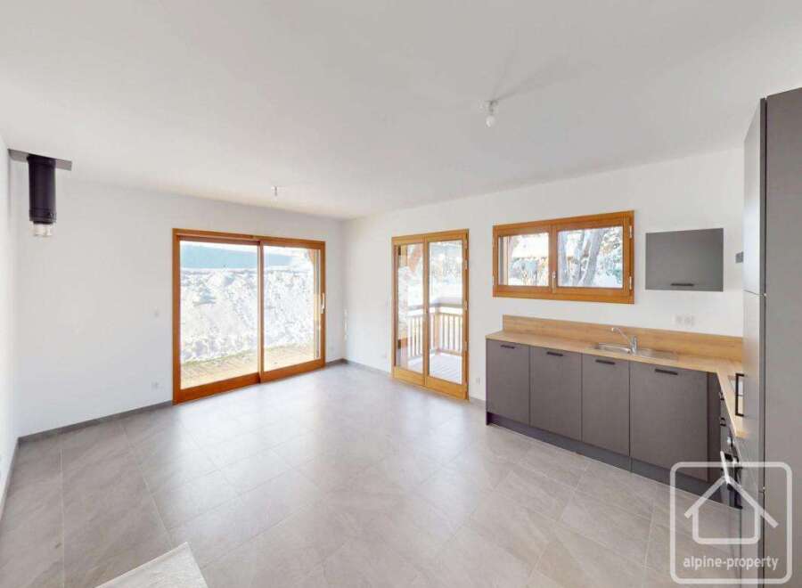 Experience modern living in this spacious open-plan room featuring a sleek grey kitchen with ample counter space and integrated appliances.