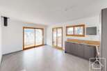 Experience modern living in this spacious open-plan room featuring a sleek grey kitchen with ample counter space and integrated appliances.