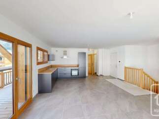 Step into this modern open-plan living space featuring a sleek, contemporary kitchen with dark cabinetry and wooden countertops.