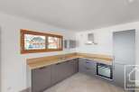 This modern kitchen features sleek grey cabinetry complemented by warm wooden countertops and a stainless steel range hood.