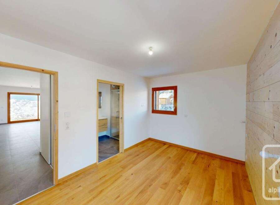 Experience modern living in this beautifully appointed room featuring warm wooden floors and a striking wood-paneled accent wall.