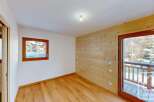 Experience cozy living in this charming room featuring warm wooden paneling and a large window offering picturesque snowy views.